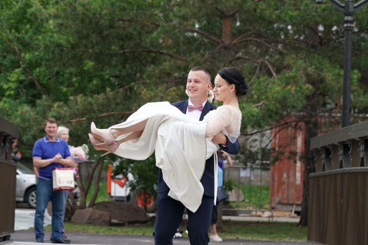 Жених несет невесту, а позади стоит Сергей Еремин с подарками