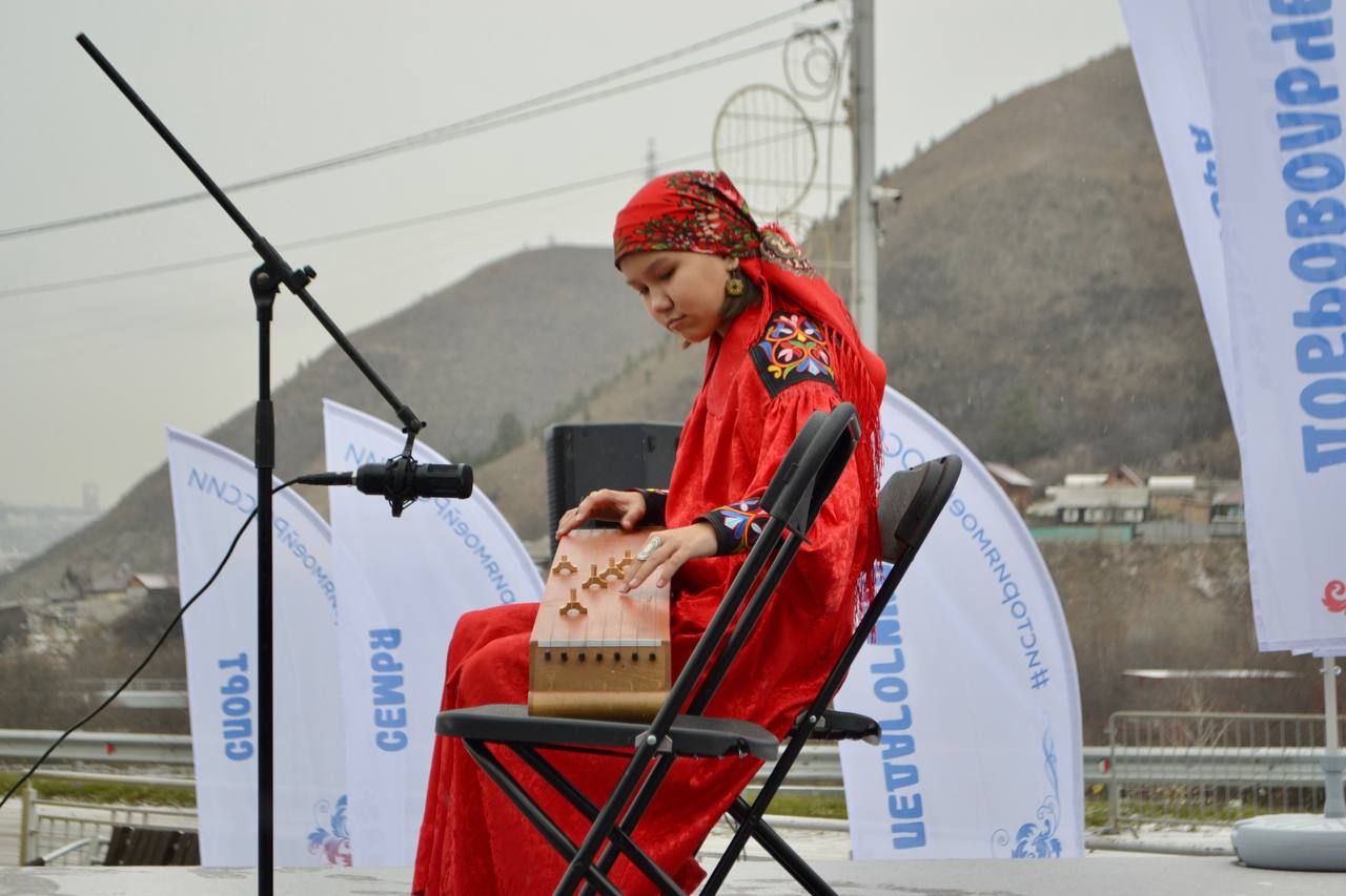 девушка в этническом костюме играет на инструменте