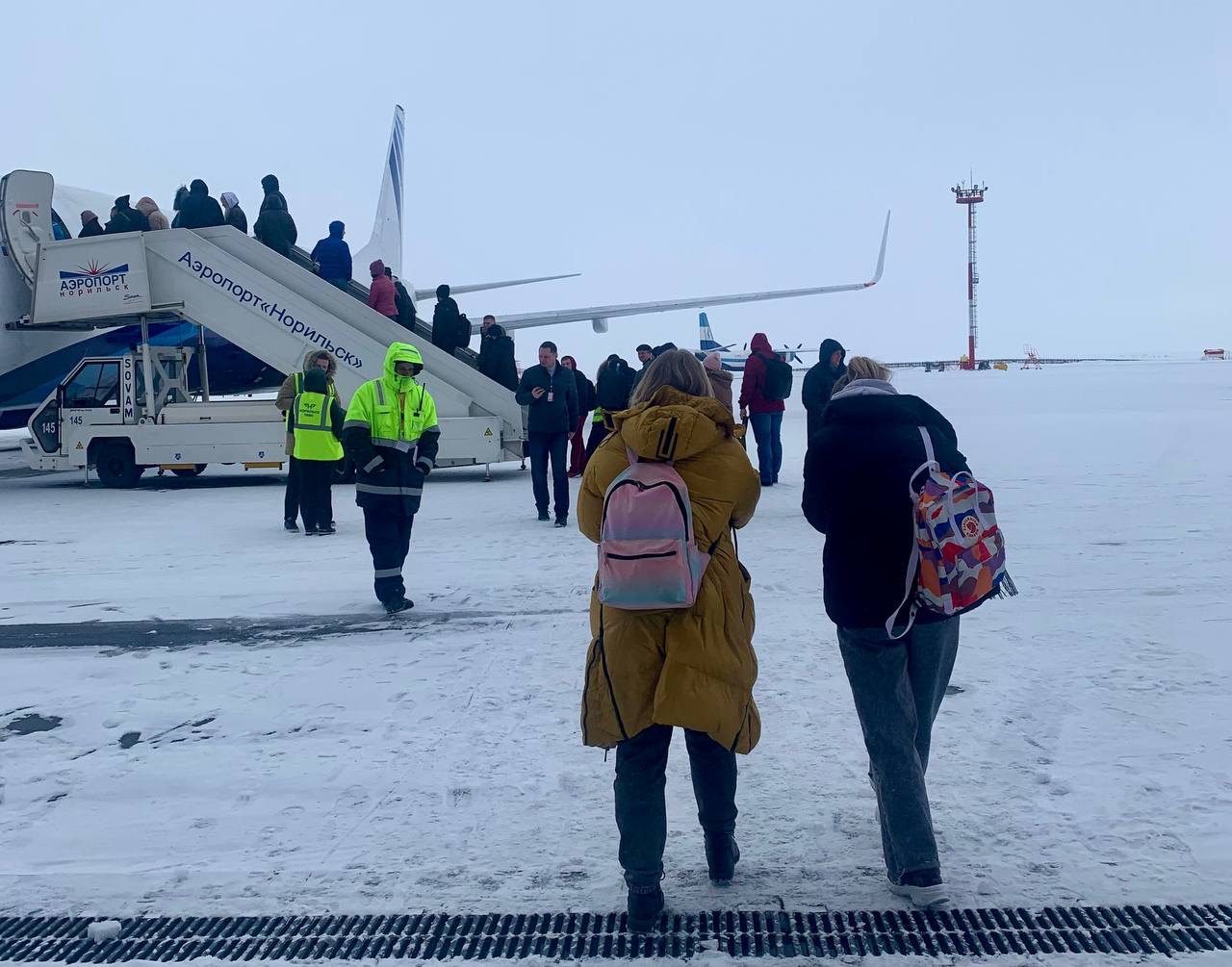 люди идут на посадку в самолет зимой