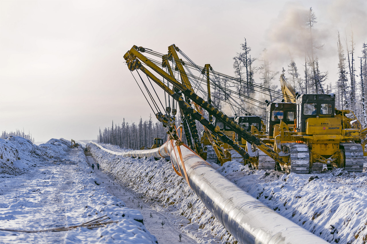 Прокладка газопровода зимой через Сибирь - тракторы укладывают трубу в траншею