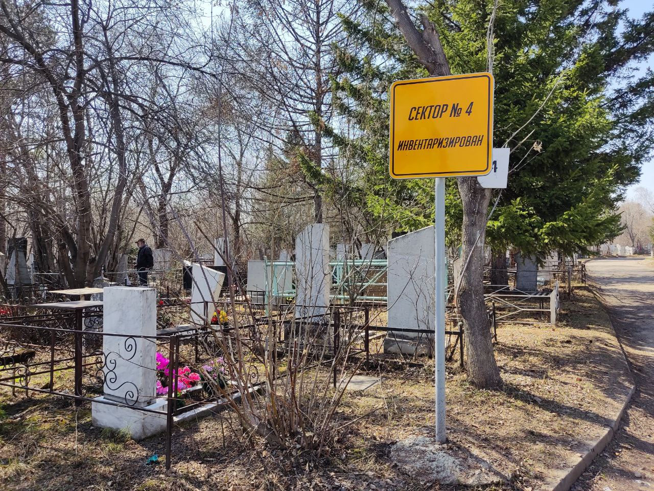 табличка инвентаризации кладбищ красноярска на фоне могил