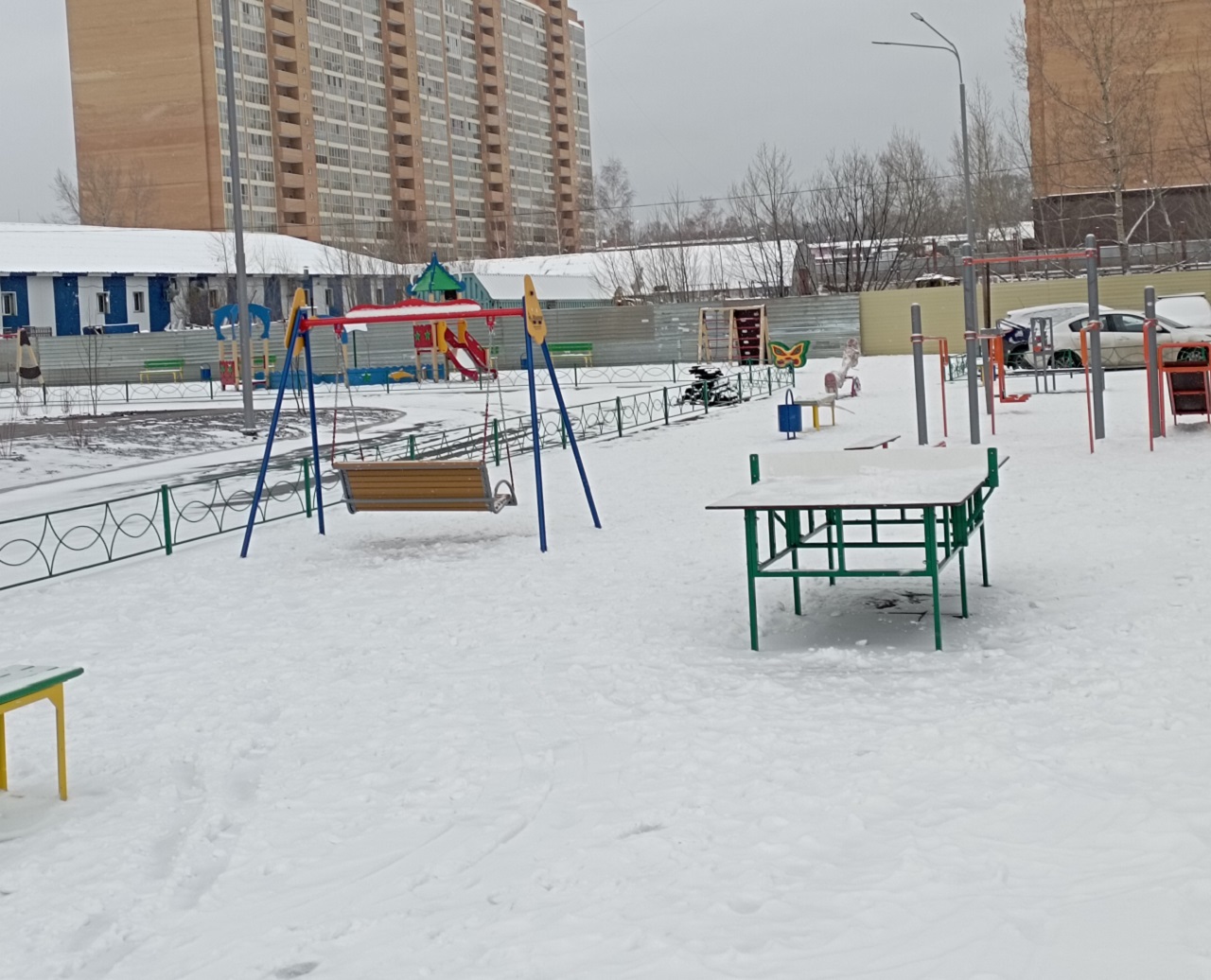 детская площадка возле многоэтажного дома зимой