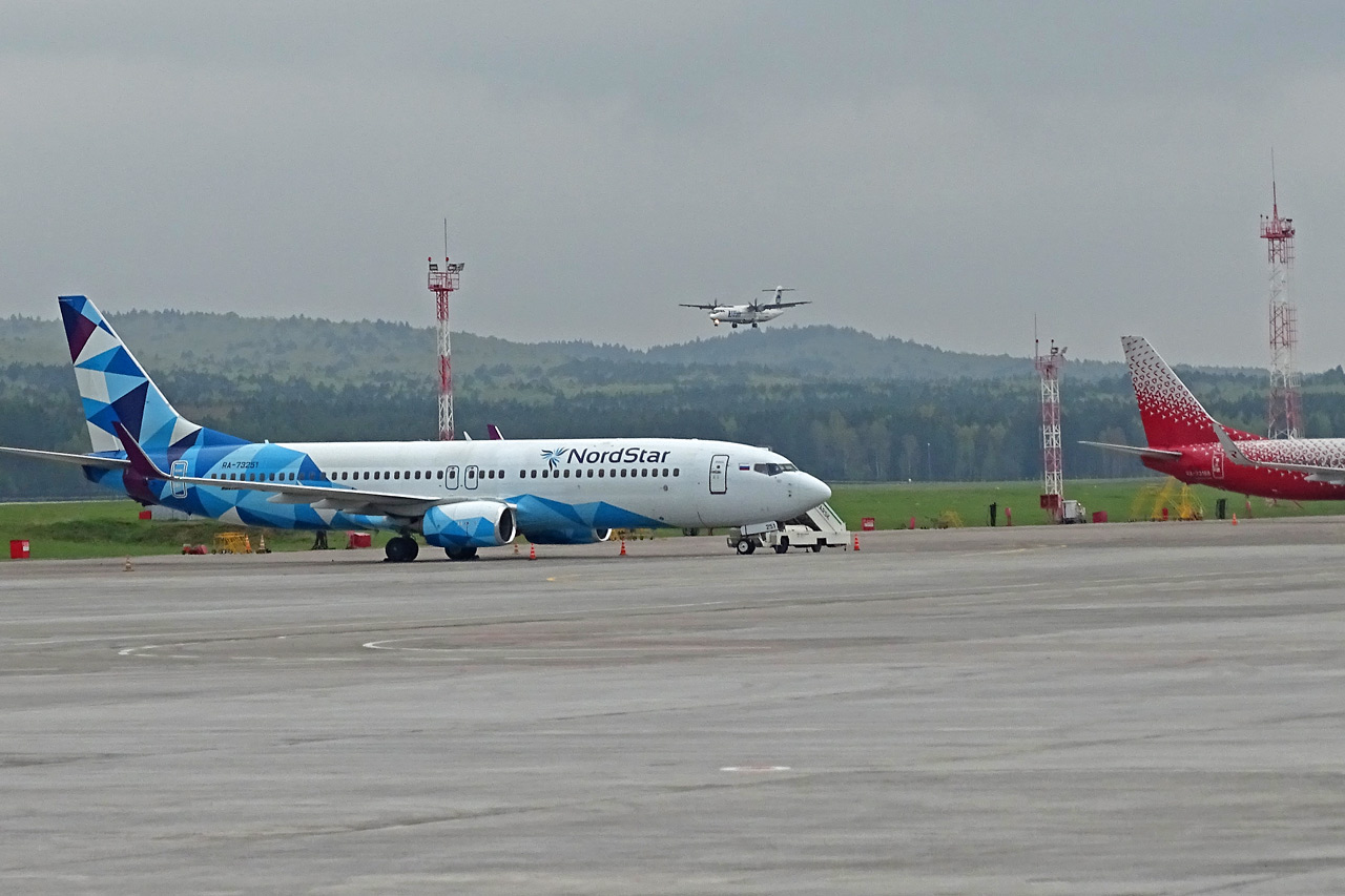 Самолет NordStar на перроне и самолет идет на посадку в аэропорту Красноярска