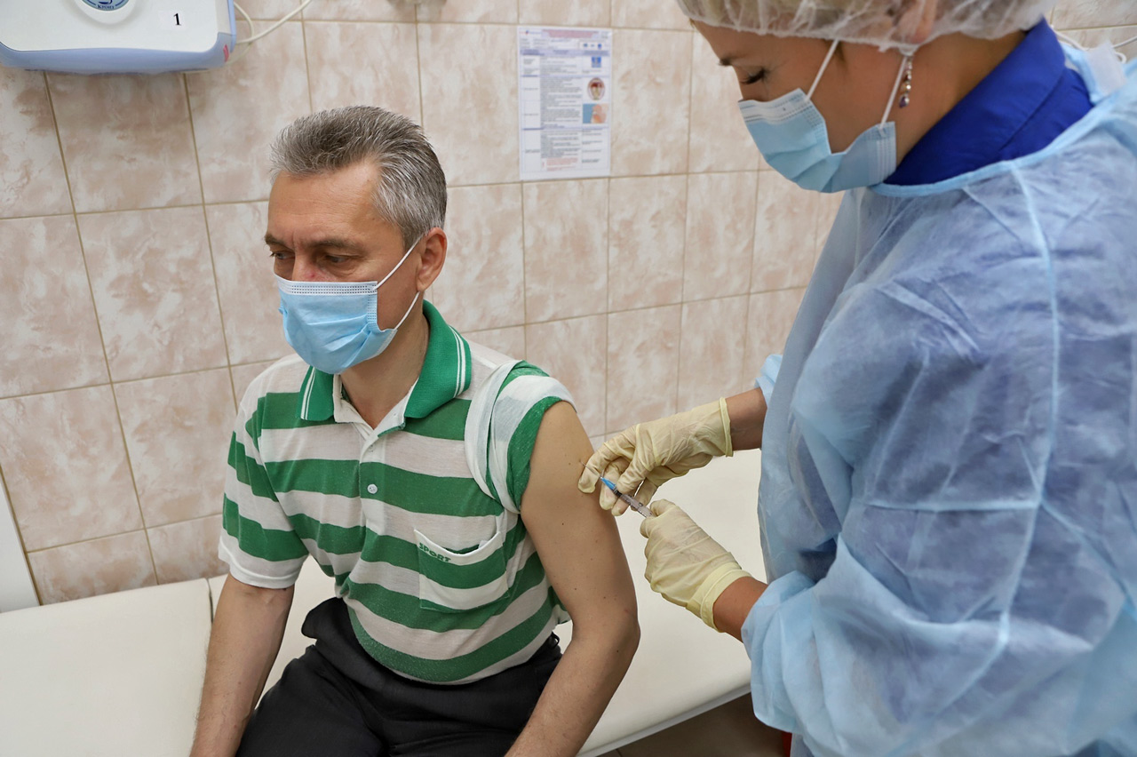 Пожилому мужчине ставят прививку - вакцинация от ковида в руку